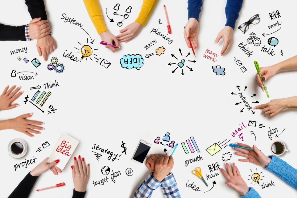 hands in a circle on a table with different business words written around